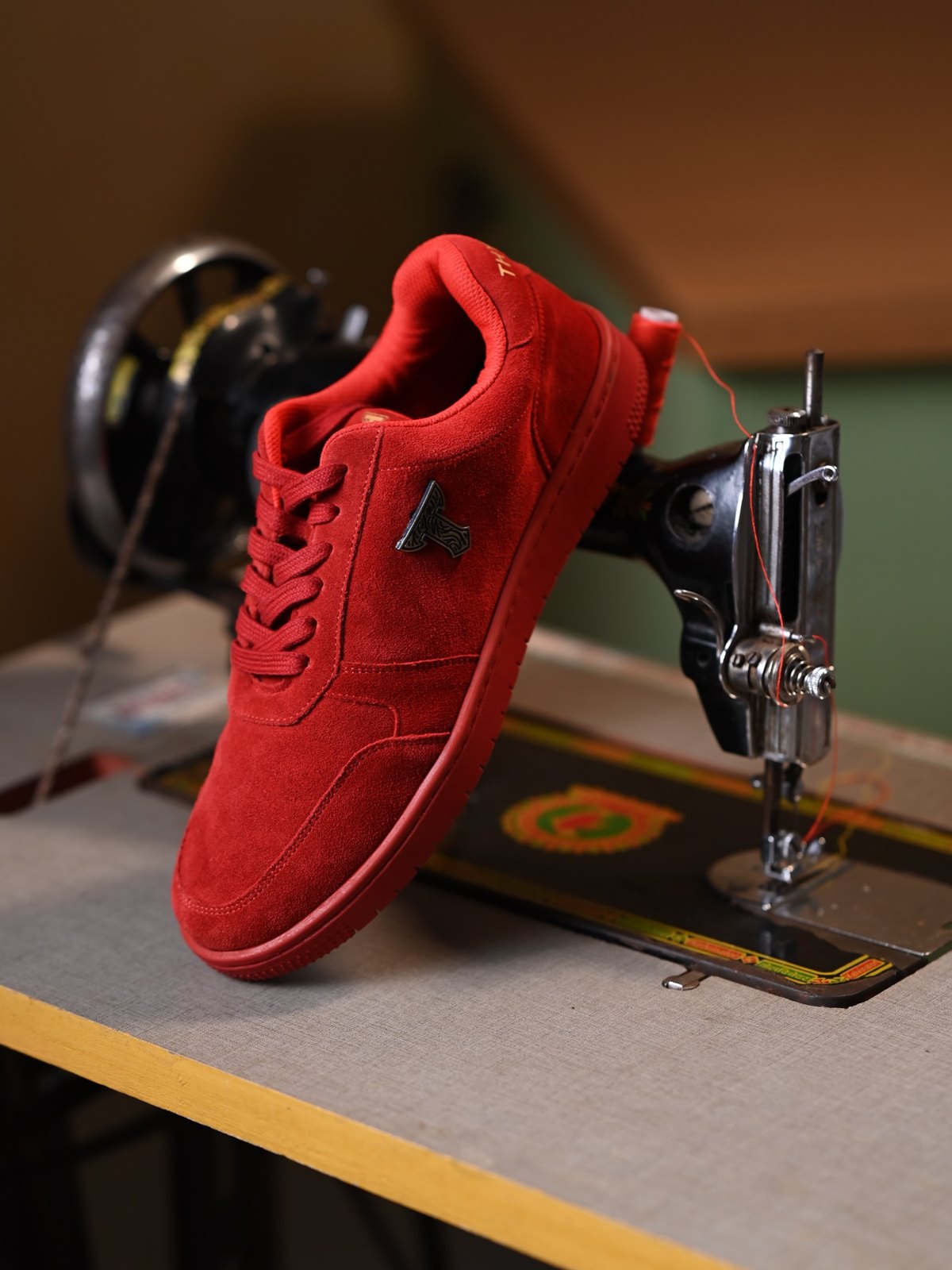 Red suede THYLACIN sneaker on a vintage sewing machine