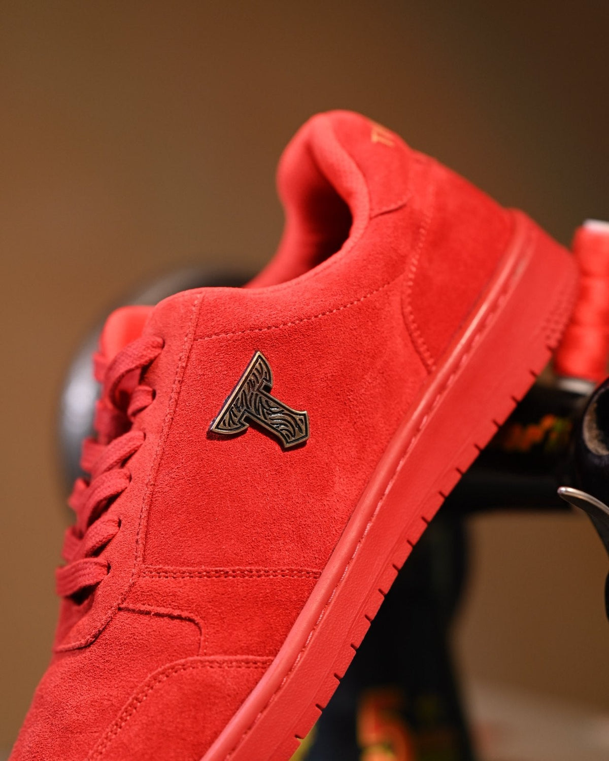Red suede THYLACIN sneaker with the metal T emblem, close up