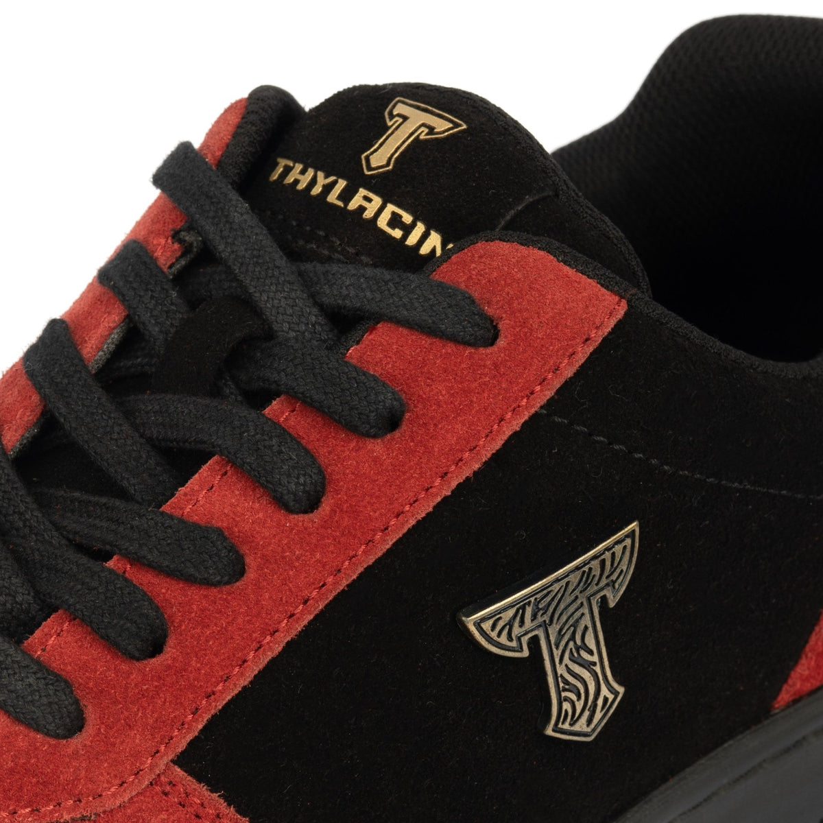 Thylacin Ember Wolf low-top sneaker in crimson red and black suede — close-up of the suede and logo badge on the shoe