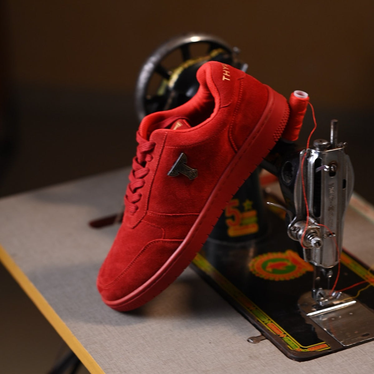Red suede THYLACIN sneaker under a vintage sewing machine