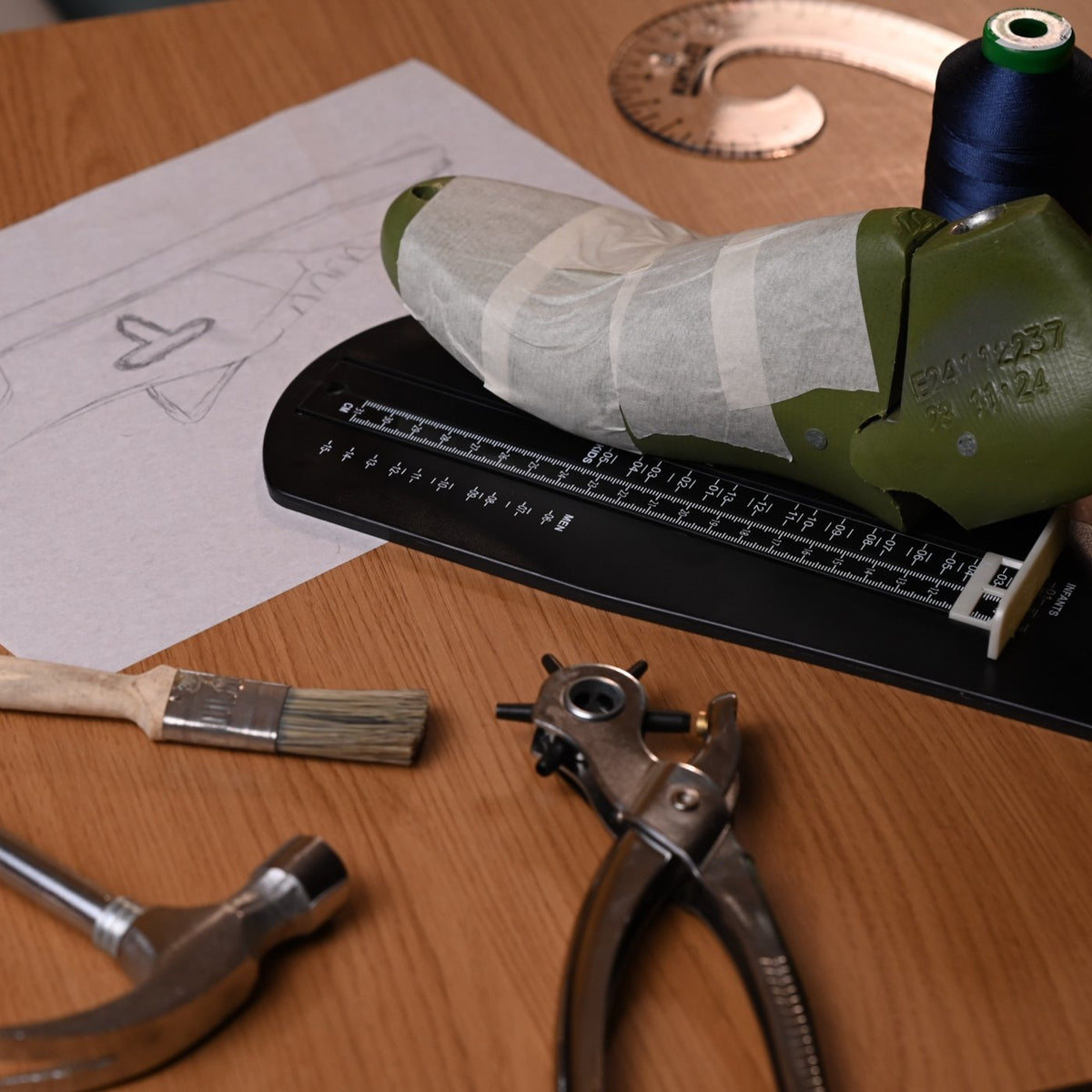 Taped shoe last on a sizing stick with hammer, brush and punch pliers