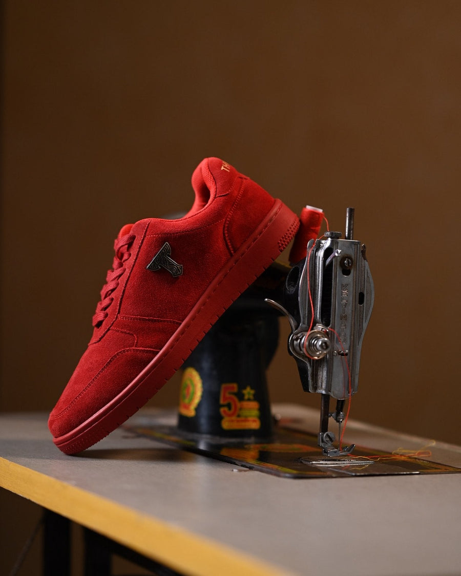 Red suede THYLACIN sneaker on a sewing machine table