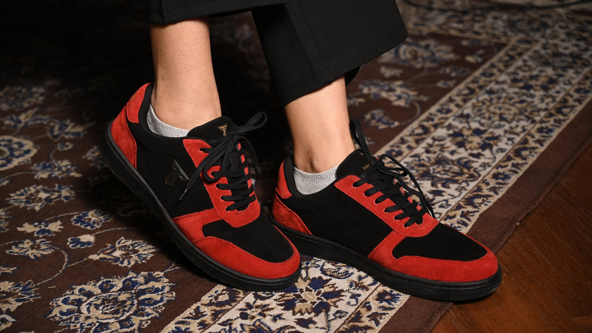 Ember Wolf red-and-black sneakers worn on a Persian rug